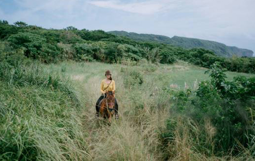 Woman riding Yonaguni native horse through farm trail, Yonaguni Island of Yaeyama Islands, Okinawa, Japan